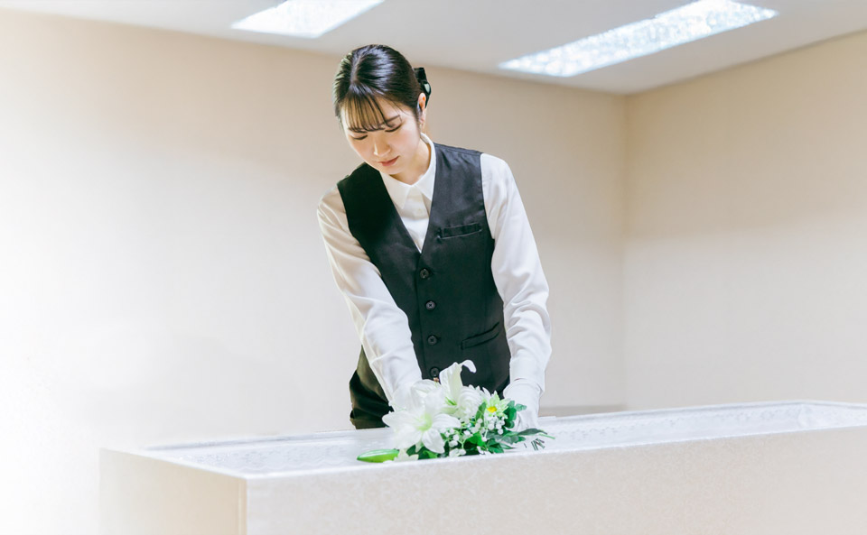 朝霞市葬儀社 アトラスが白い棺に花を飾りご安置の準備をするスタッフ